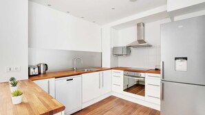 Une cuisine moderne avec des meubles blancs, une hotte en acier inoxydable et un four encastré.