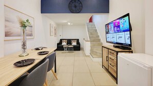 Un salon moderne comprenant un coin repas, un canapé, un téléviseur et un escalier.