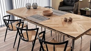 A modern dining area with a wooden table, black chairs, and a cushioned bench.