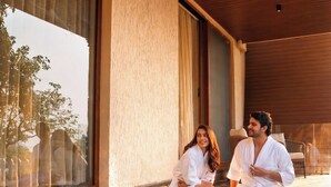 A couple in white robes by a pool with a breakfast tray. - ARK Lake Resort (Igatpuri)