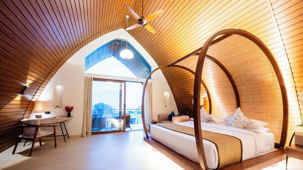 A bedroom with a curved ceiling, a bed, a desk, and a view of the outdoors. - ARK Lake Resort (Igatpuri)