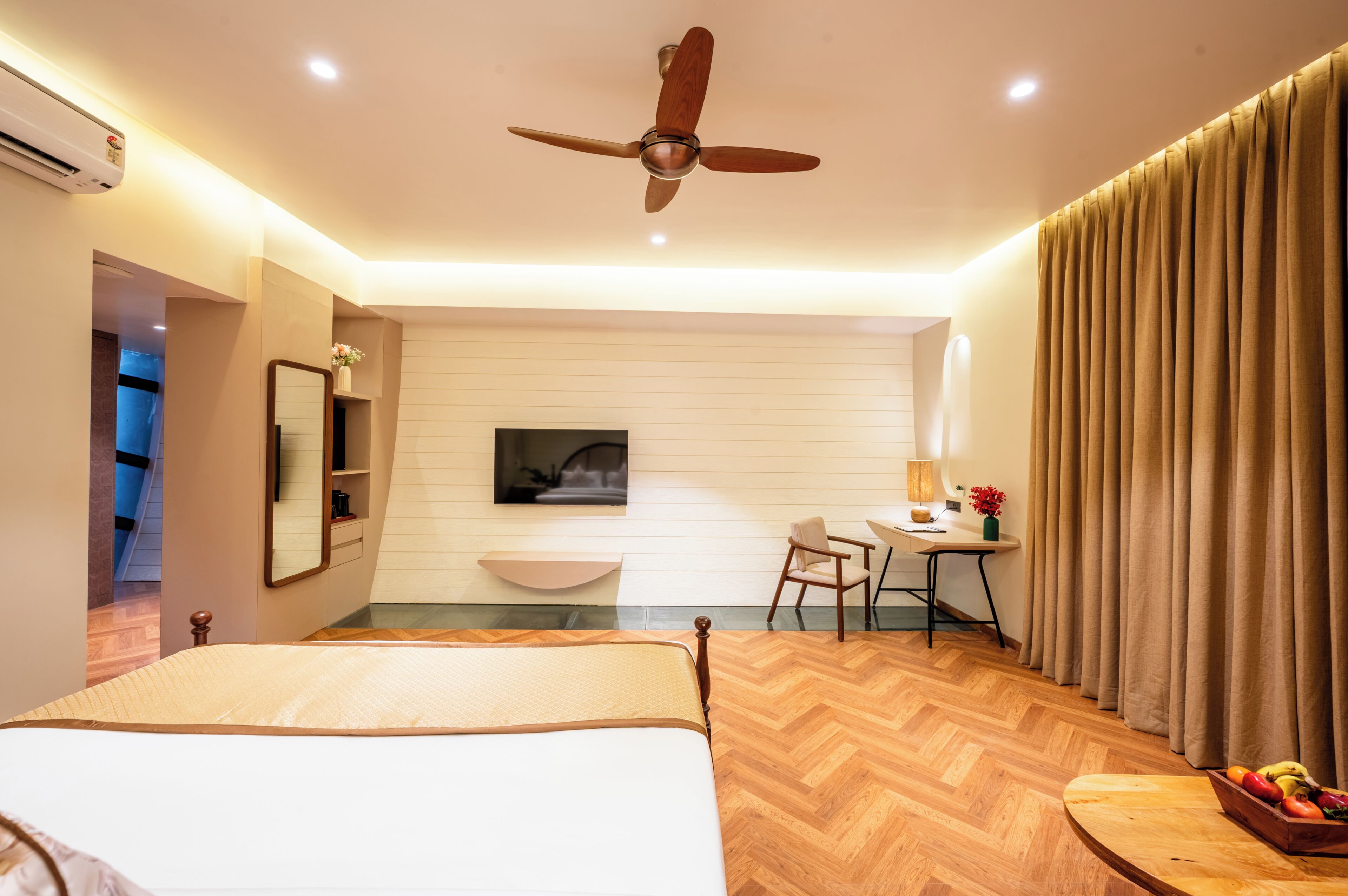 Une chambre d’hôtel équipée d’un lit, d’un bureau, d’une chaise, d’une télévision et d’un ventilateur de plafond.
