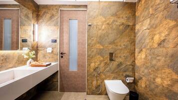 A modern bathroom with a marble wall, a white sink, and a shower area.