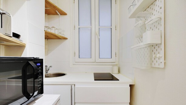 Una cucina funzionale con forno a microonde, lavello e mobili bianchi.