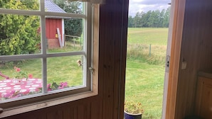 Puerta de madera que da a un jardín con un cobertizo rojo al fondo.