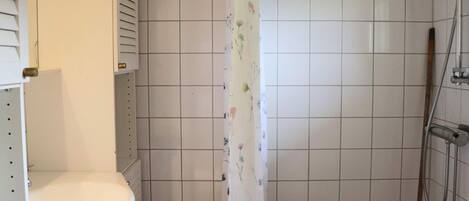 A bathroom with a white sink, a shower with a handheld showerhead, and a floral shower curtain.