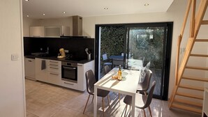 Une cuisine moderne avec des meubles blancs, un plan de travail noir et un coin repas comprenant une table et des chaises.