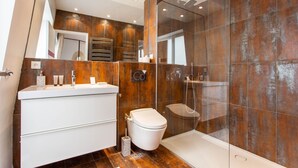 Un baño moderno con tocador blanco, inodoro y zona de ducha con mampara de vidrio.