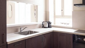 Una cocina moderna con lavavajillas integrado, un lavamanos doble y un ventanal que proporciona luz natural.