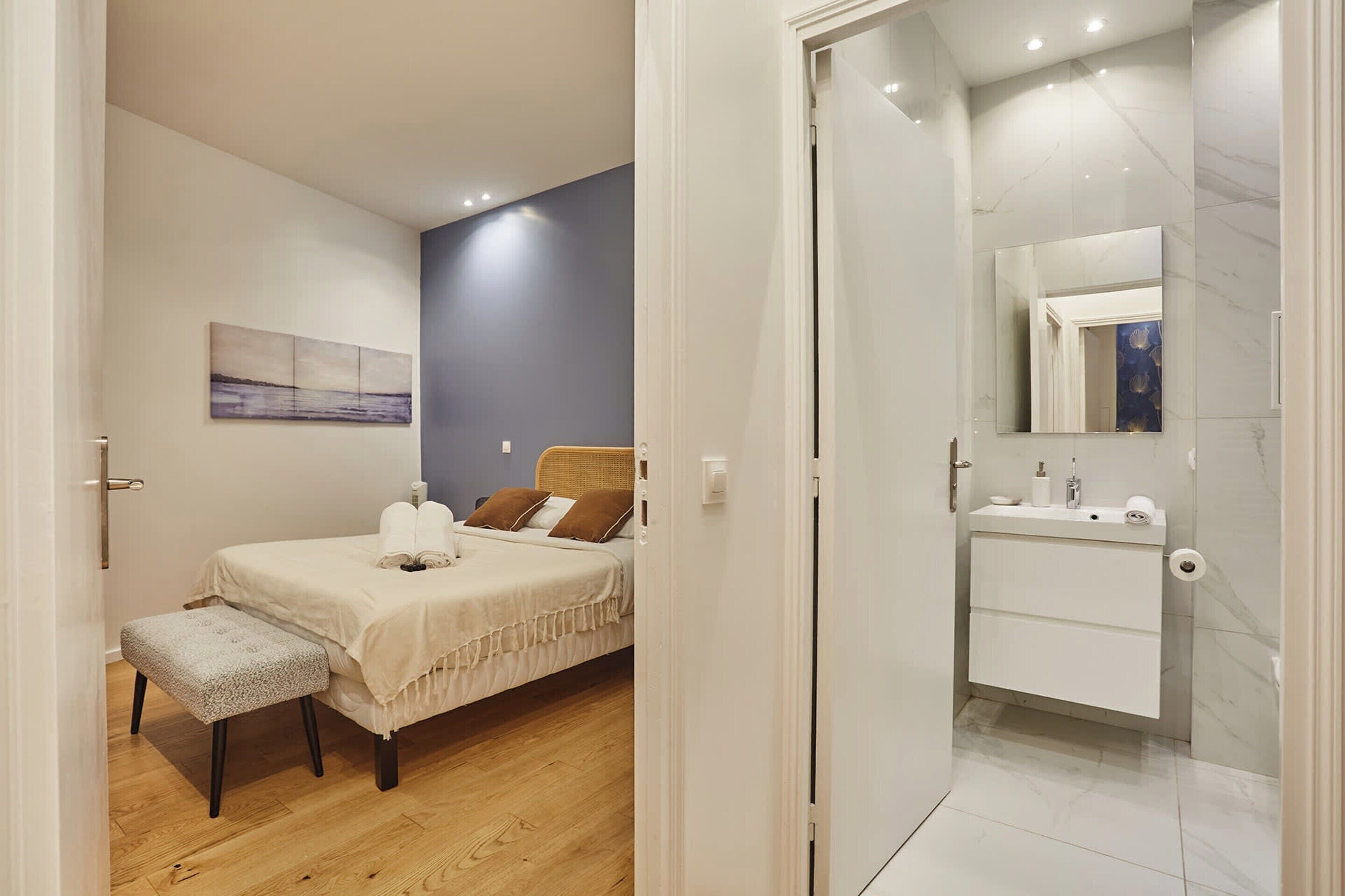A bedroom with a bed, bedside table, and a bench.