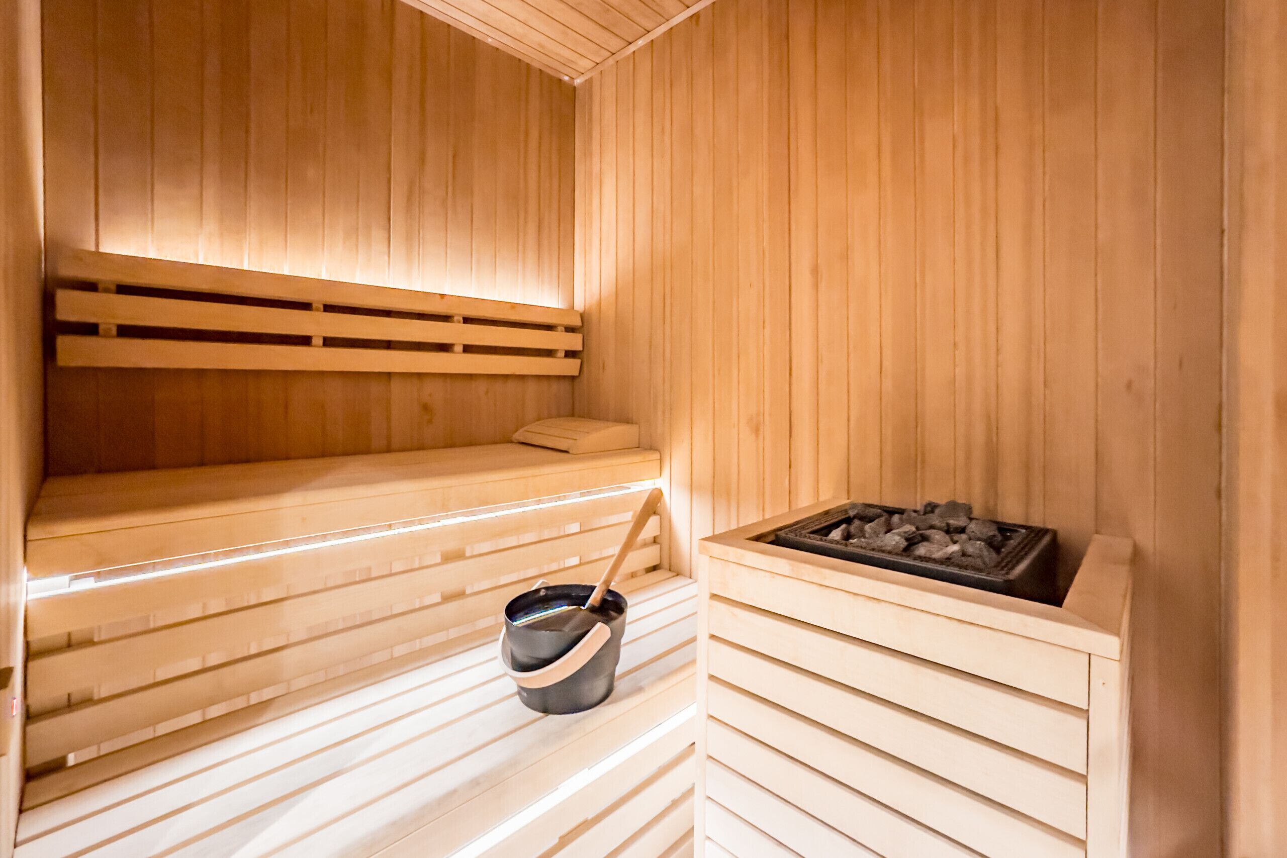 Sauna, jossa on puiset lauteet ja kivinen allas sekä kauha.