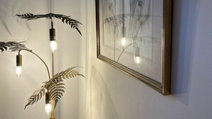 A framed horse painting on a wall, a floor lamp with leaf-shaped shades, and a light bulb.