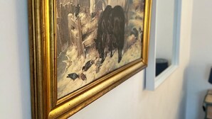 A framed painting of a stable scene with horses and a barn.