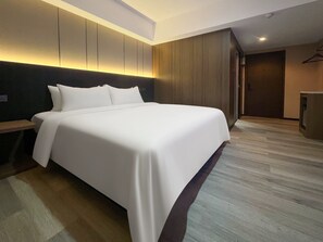 A modern hotel room with a large bed, a wooden headboard, and a built-in wardrobe. - X Hotel Pattaya (Pattaya)