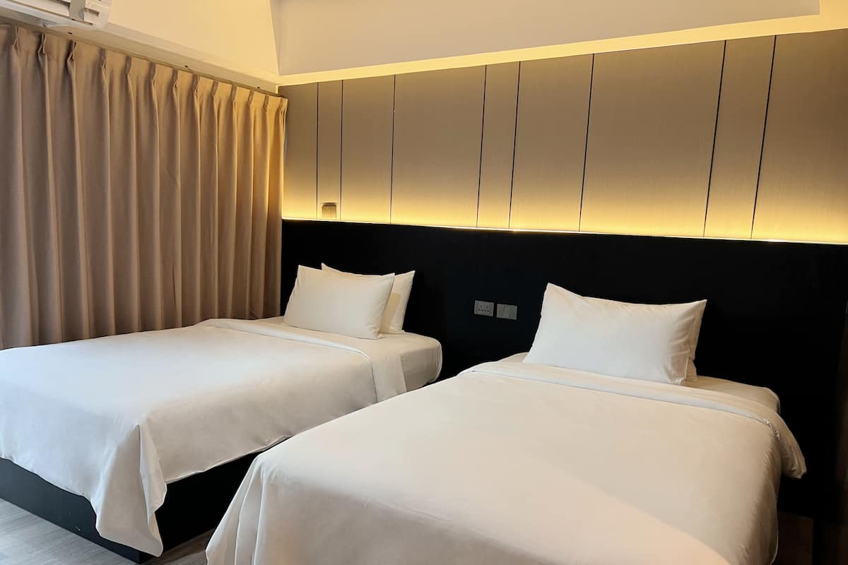Dos camas individuales con sábanas blancas en una habitación de hotel.