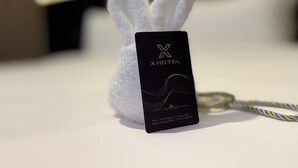Una tarjeta negra con 'XHOTEL' y detalles de la dirección sobre una superficie blanca.