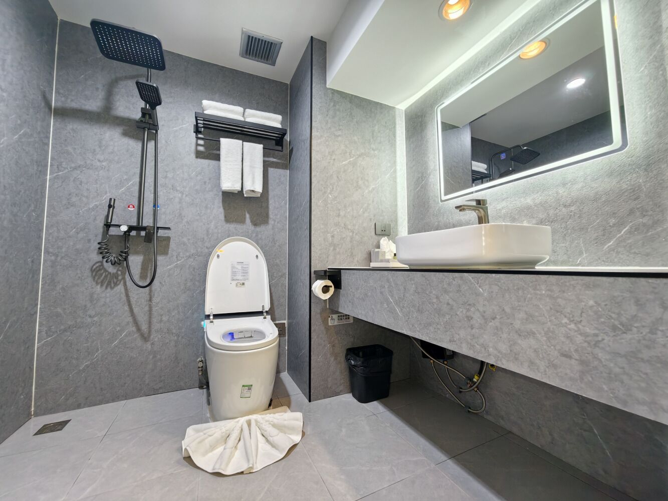 A modern bathroom with a toilet, shower, and sink.