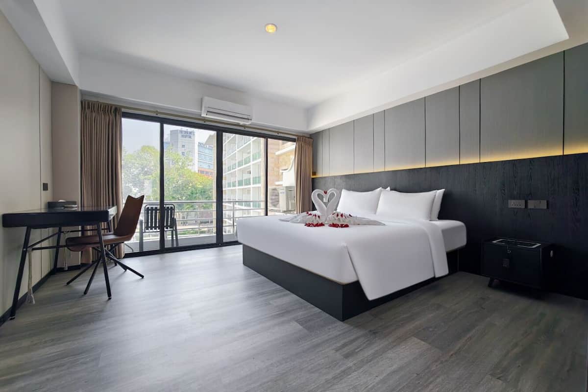 Una habitación de hotel moderna con una cama grande, un escritorio y vistas a la ciudad.