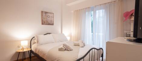 A neatly arranged bedroom with a bed, bedside table, and a TV on a dresser.