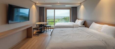 A hotel room with two beds, a TV, a small table, and a balcony with a view.