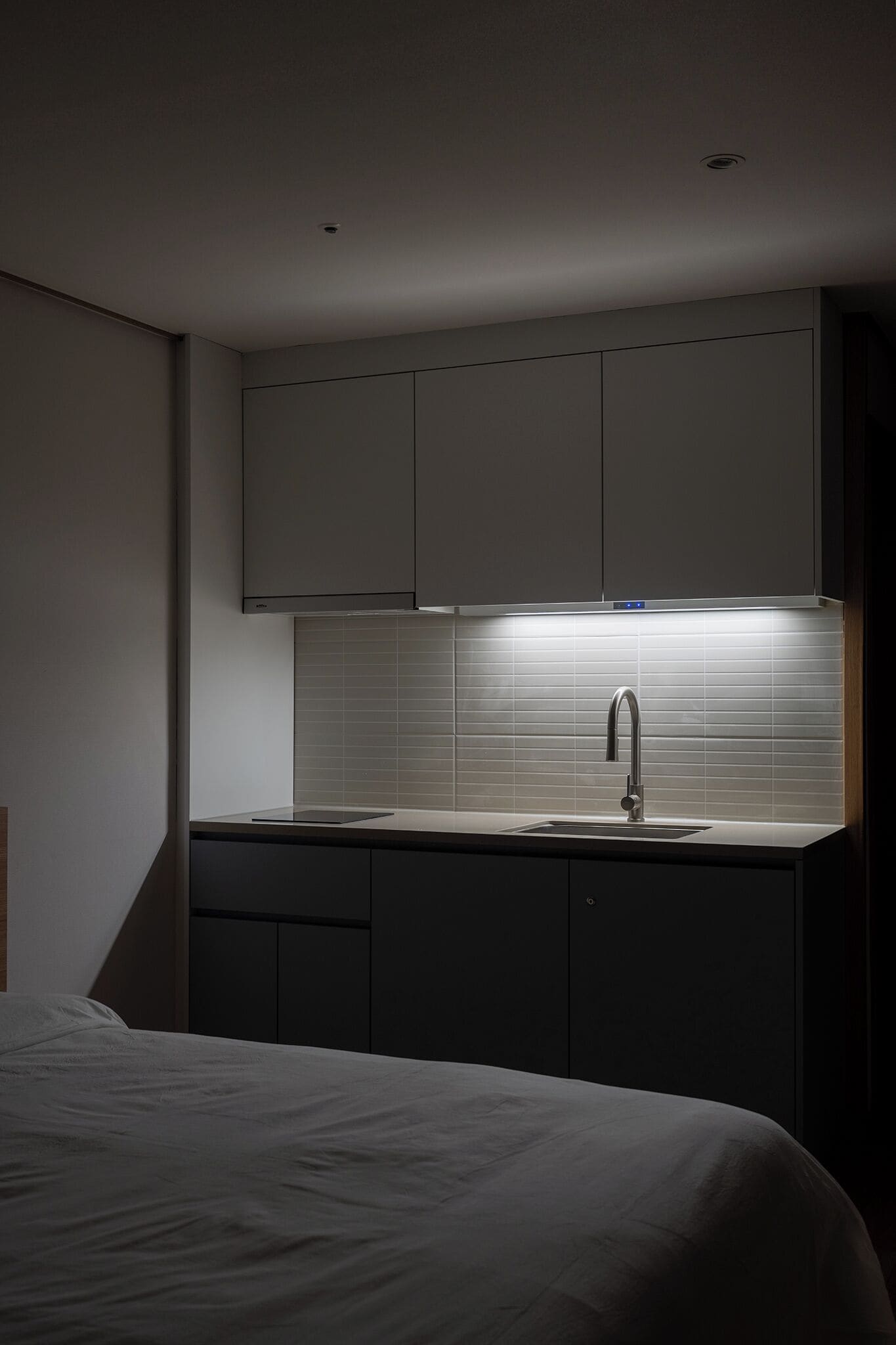 A modern bedroom with a bed, a bedside table, and a built-in wardrobe.