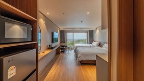 A hotel room with a bed, a desk, a TV, and a refrigerator.