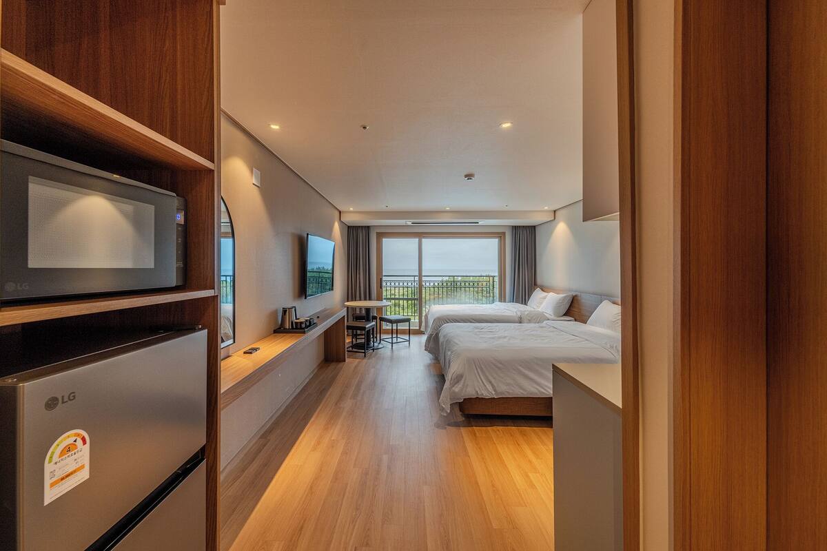 Una habitación de hotel con cama, escritorio, televisor y refrigerador.