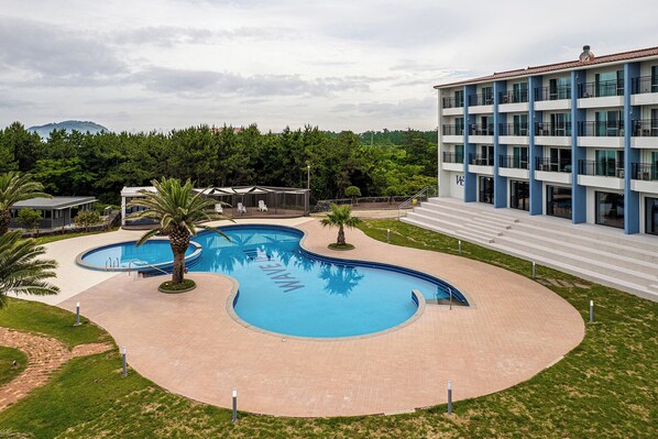Una piscina con diseño ondulado, rodeada por un sendero de ladrillo y palmeras.