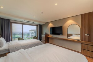 Habitación de hotel con dos camas, televisión, espejo y balcón con mesa y sillas.