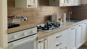 A kitchen with white cabinetry, a gas stove, and a stainless steel sink. - Modern and Cozy Oasis in the Heart of the City (Civitavecchia)