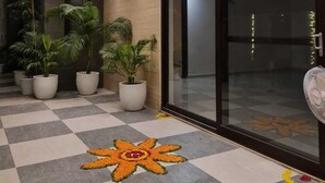 A hotel corridor with a checkered floor, potted plants, and a glass door leading to a room. - RAMYA STAYS (Lucknow)