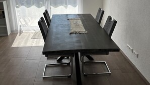A modern dining room with a large table, chairs, and a view through a glass door. - Fantastic vacation apartment (Altendorf)