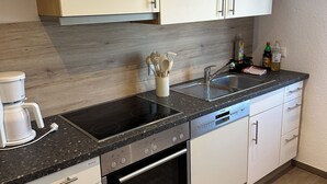 A modern kitchen with white cabinets, a black countertop, a built-in oven, and a coffee maker. - Fantastic vacation apartment (Altendorf)