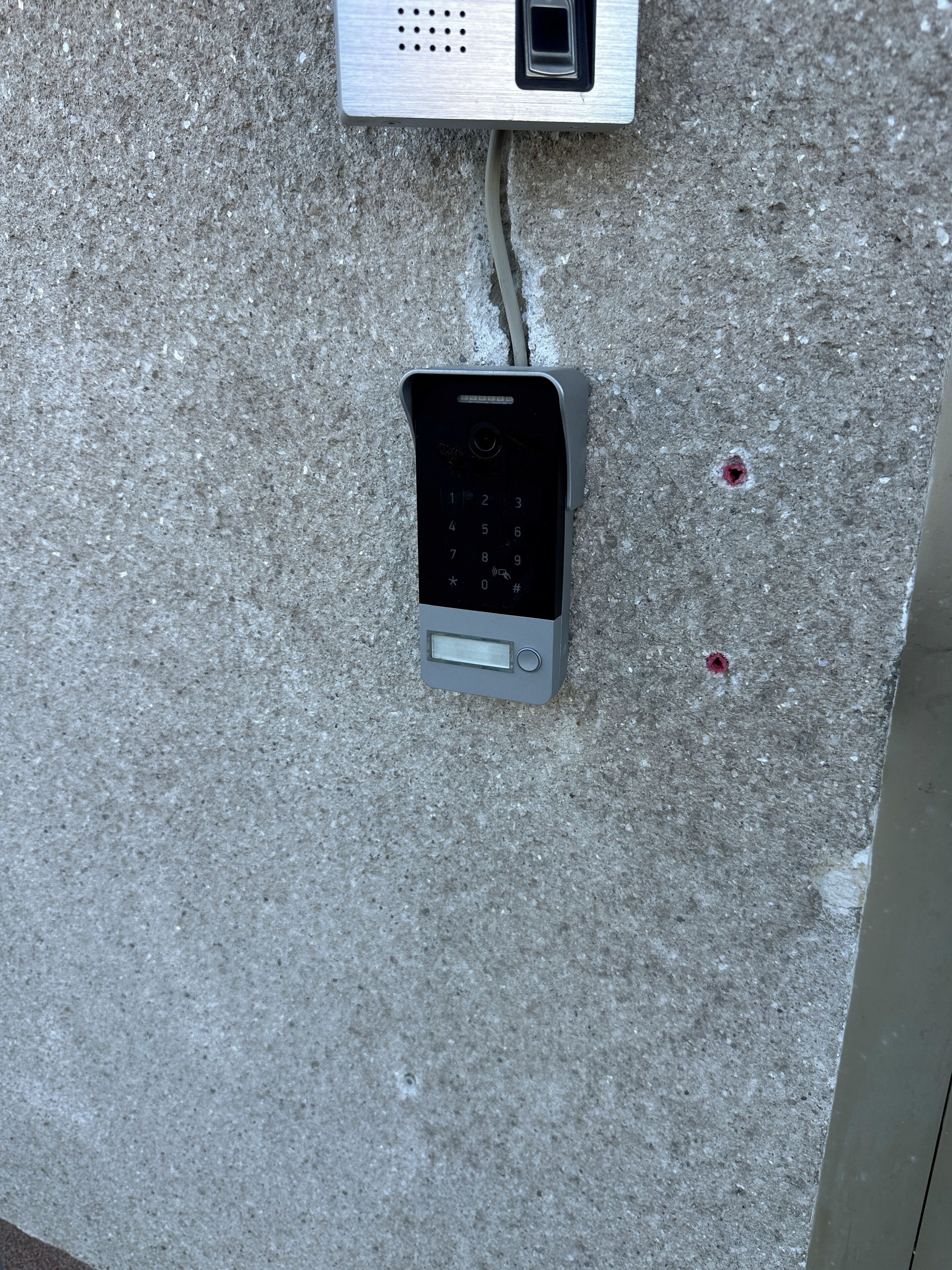 Et tastatur monteret på en betonvæg, forbundet med et større panel over det.