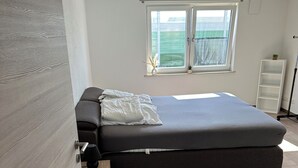 A bedroom with a bed, a window, a white shelf, and a door. - Fantastic vacation apartment (Altendorf)