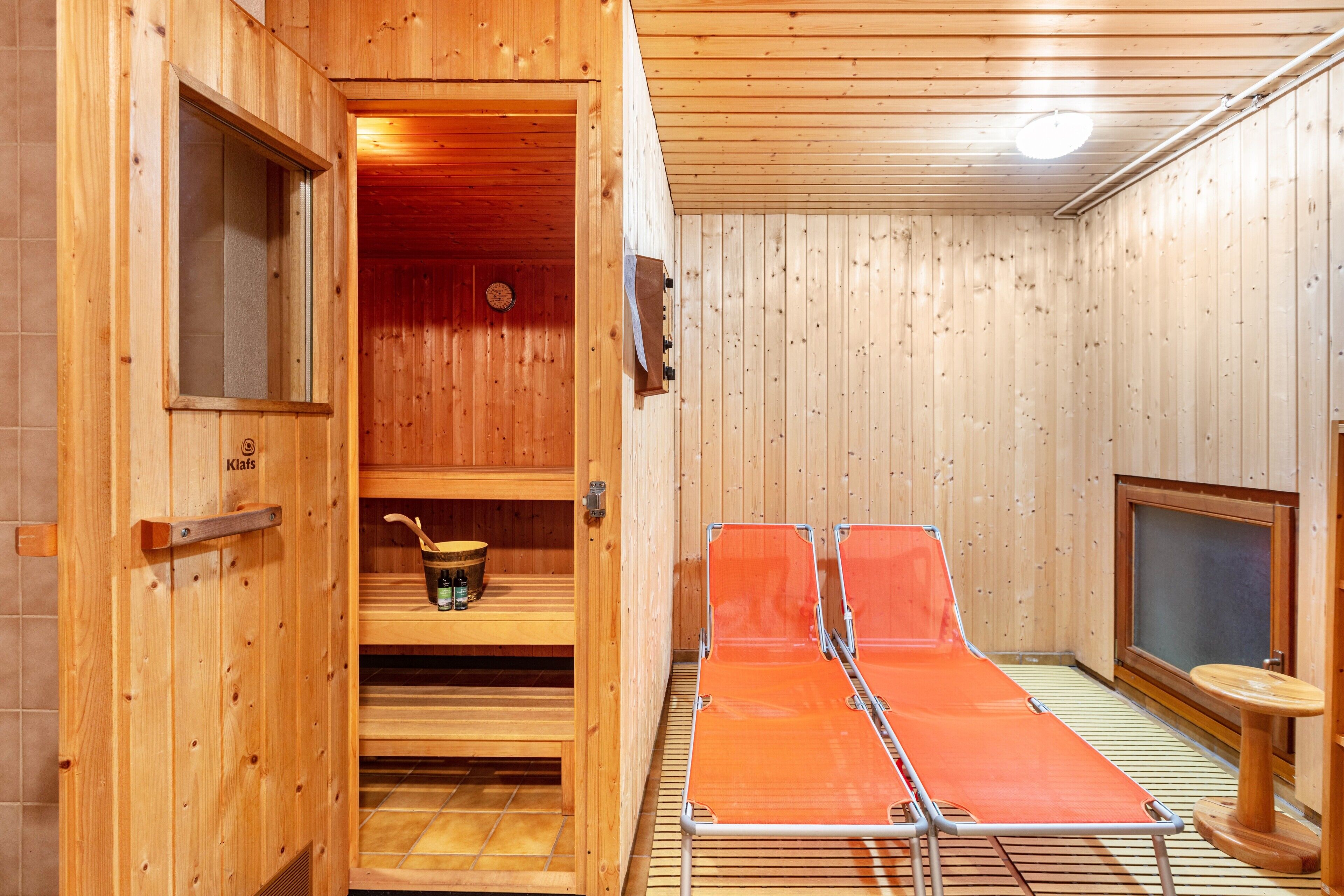 Un sauna avec des murs en bois, un banc, une étagère avec un seau et une petite table.
