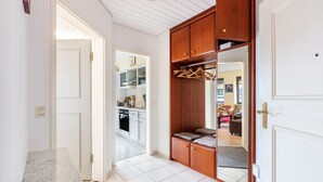 Un couloir avec une armoire en bois, un comptoir en marbre et une vue sur une cuisine.