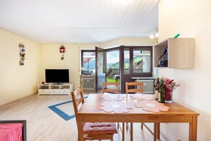 A dining area with a table, chairs, a television, and a view of the outdoors. - Apartment "Blütenzauber" with Mountain Views, Private Terrace and Wi-Fi (Todtnau)