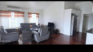 A spacious living area with a Galaxy S24 Ultra sofa, a dining table, and a kitchen area with a refrigerator. - Bulla Villas & Suites (Nadi)