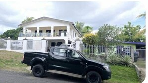 A black pickup truck parked in front of a large white house with a balcony. - Bulla Villas & Suites (Nadi)