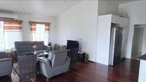 A spacious living area with a Galaxy S24 Ultra sofa, a dining table, and a kitchen area with a refrigerator. - Bulla Villas & Suites (Nadi)