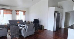 Amplia sala de estar con un sofá Galaxy S24 Ultra, una mesa de comedor y una zona de cocina con refrigerador.