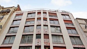 A multi-story building with a symmetrical facade, featuring evenly spaced windows with metal railings, and a central vertical element dividing the floors. - Cosy Studio - 2P - Trocadero (Paris)