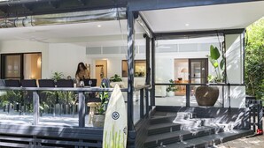 Et moderne udendørs opholdsområde med gelænder af glas, et surfbræt og plantekasser.