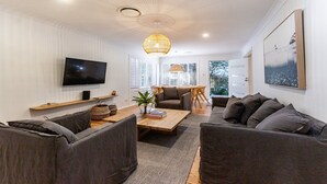 En moderne stue med et fladskærms-tv, et træsofabord og grå sofaer.