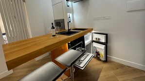 Et kompakt køkken med træbordplade, indbygget vask, mikrobølgeovn og minikøleskab.