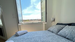 Et soveværelse med en stor seng, et vindue med udsigt og et natbord med en lampe.