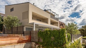 A modern two-story house with a balcony, a satellite dish, and a fenced garden area. - 2 bedroom lovely apartment in Kozino (Kozino)