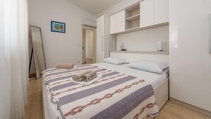 A neatly arranged bedroom with a bed, pillows, a bedside table, and a wall-mounted shelf. - 2 bedroom lovely apartment in Kozino (Kozino)