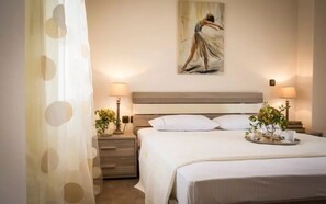 A neatly arranged bedroom with a bed, bedside tables, lamps, and a painting on the wall.